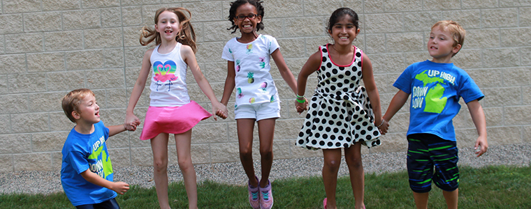 five children holding hands and jumping in the air