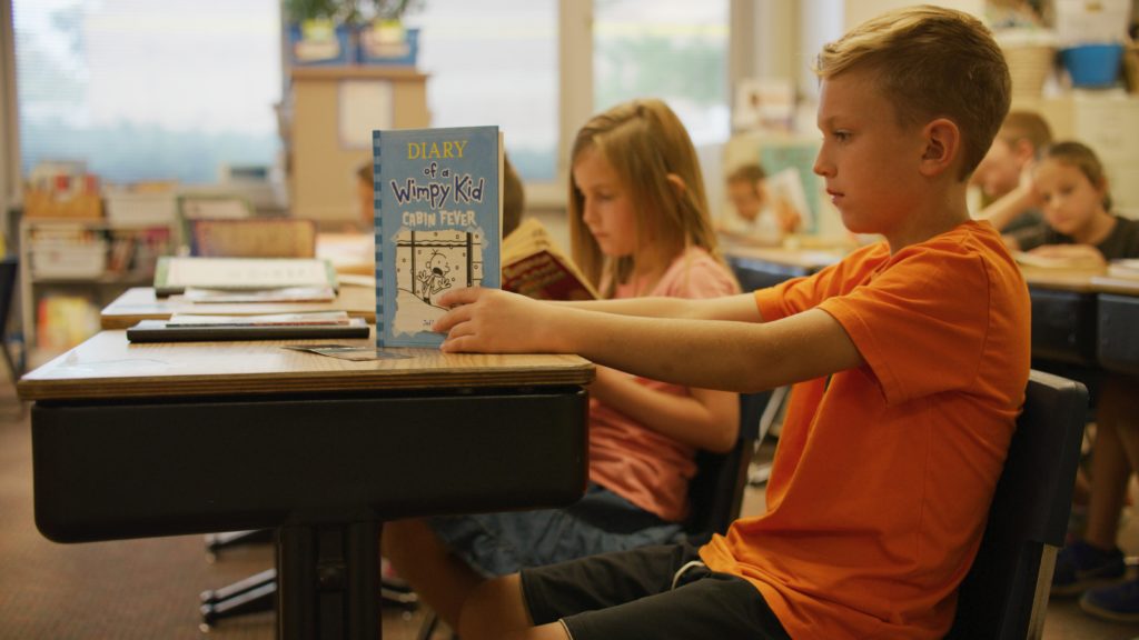 Boy reading "Diary of a Wimpy Kid" book