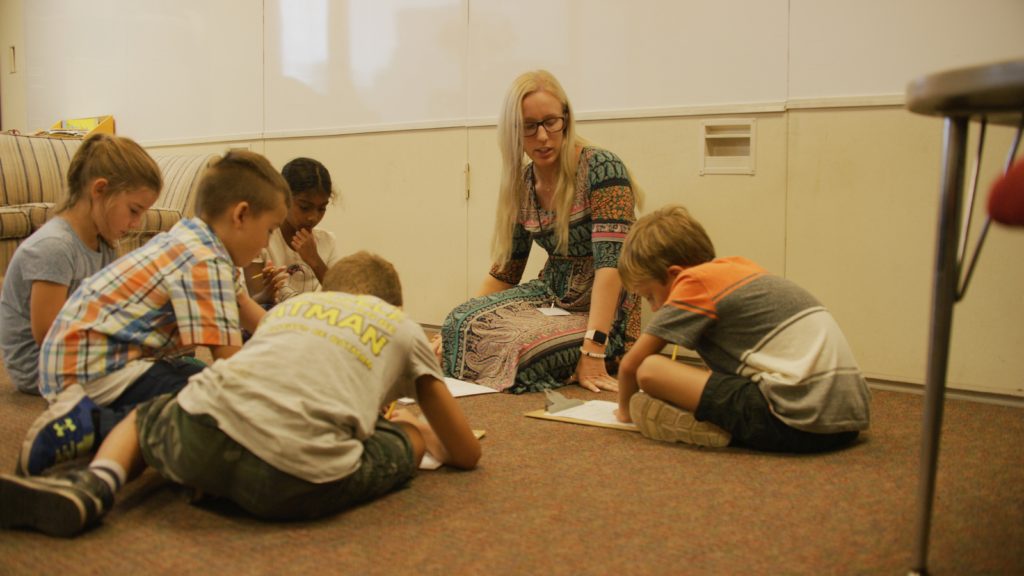 Kids sitting on the floor with a teacher.