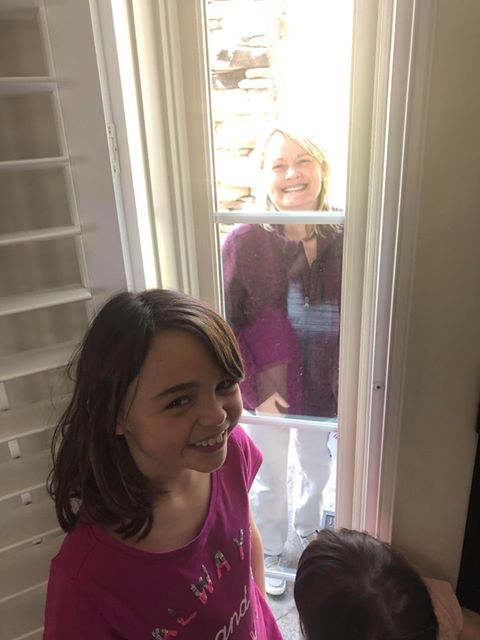a girl standing in a doorway with the door closed buy looking at a woman on the other side
