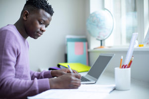teen boy sitting at desk using a laptop