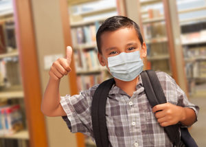 child in library giving thumbs up and a mask on