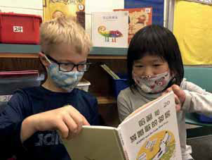 two students reading a book together