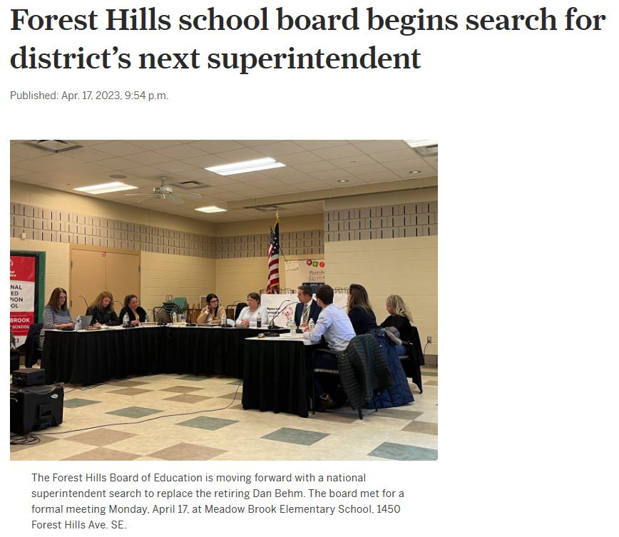 Photo of board of ed seated behind tables in a school cafeteria