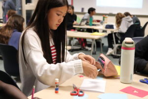 a middle school girl glues an image to the page