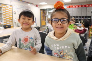 two kindergarten students smile in a classroom