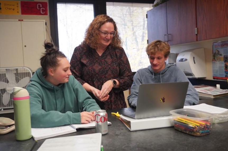 a high school female teacher works with two high schools tudents