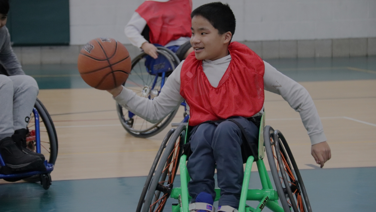 male student in a wheelchair playing basketball