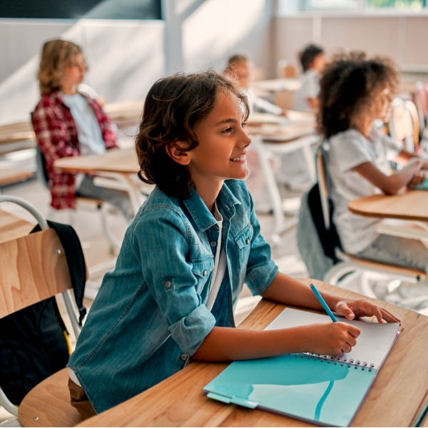 young students learning at desks in class and writing