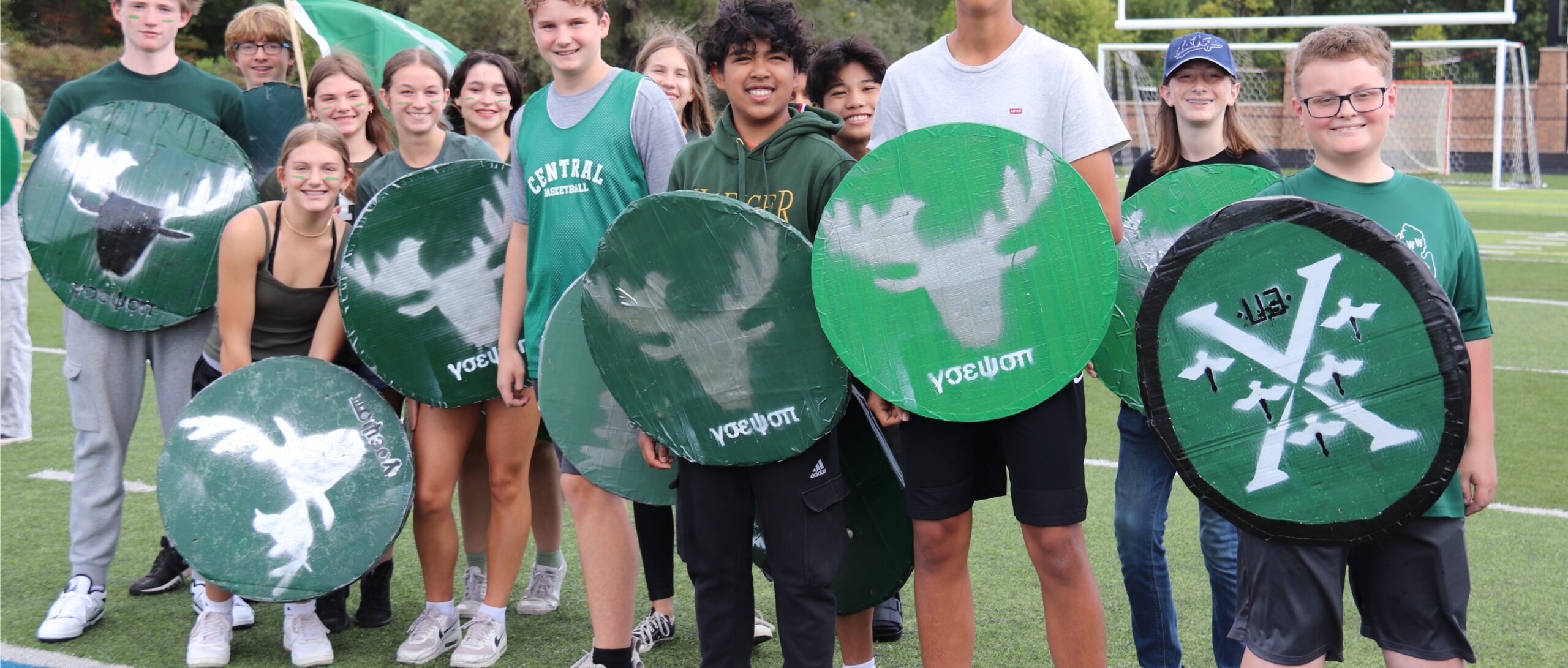 students holding their shields on a football field