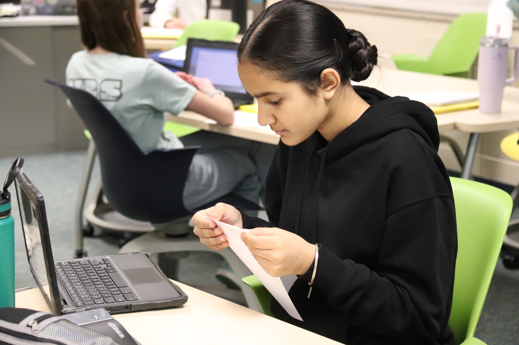 student working on a paper using her computer to help