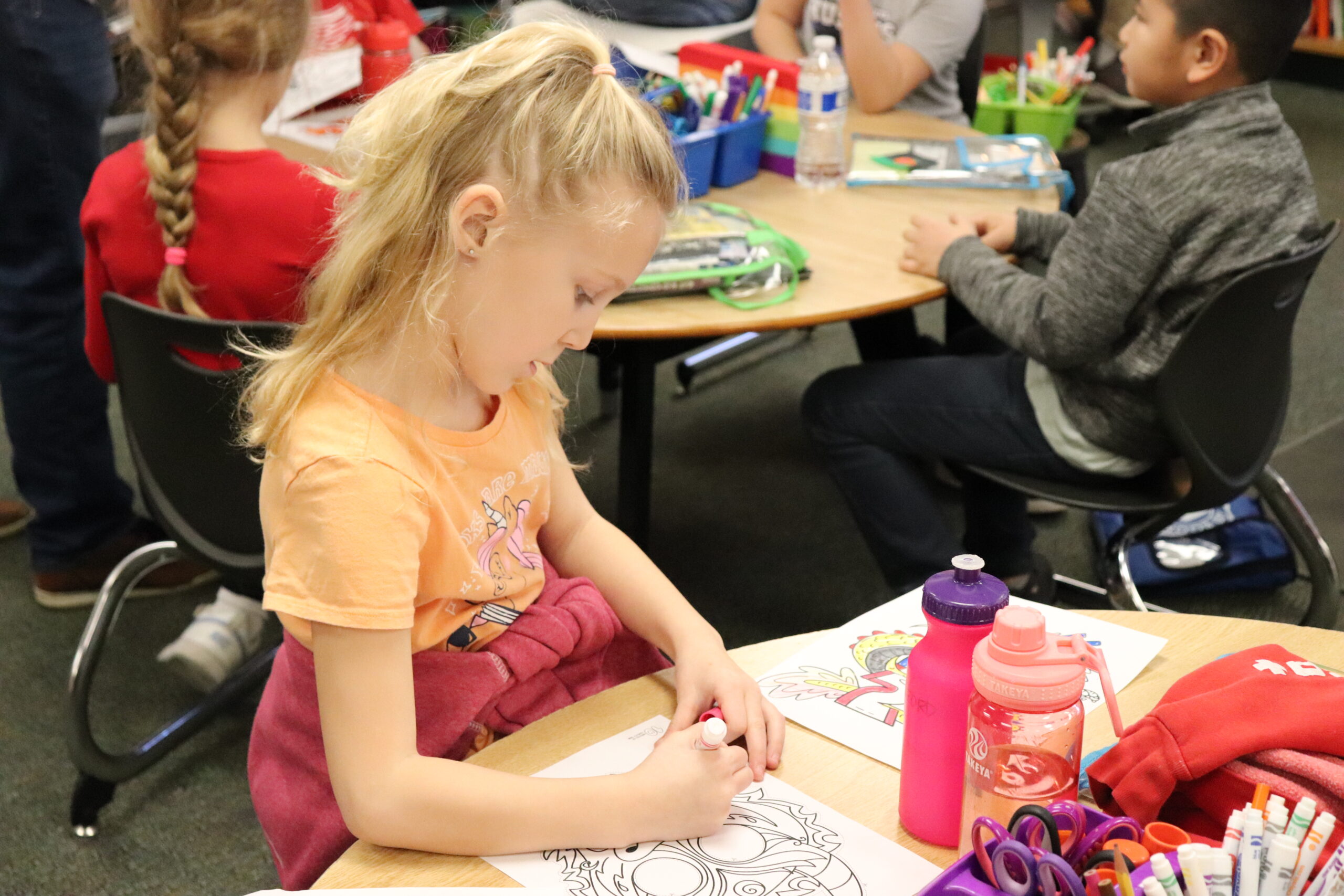 young female student working on coloring in a coloring sheet