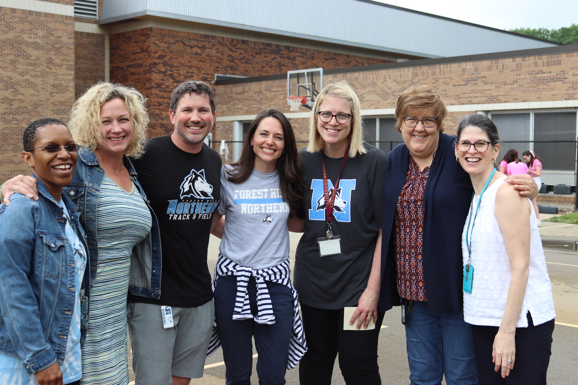 staff members posing for a picture outside the school on a basketball court