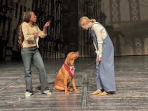 two girls on a theater stage with a dog
