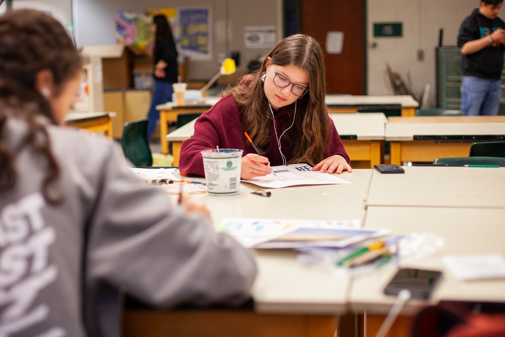student with earbuds doing work at a desk