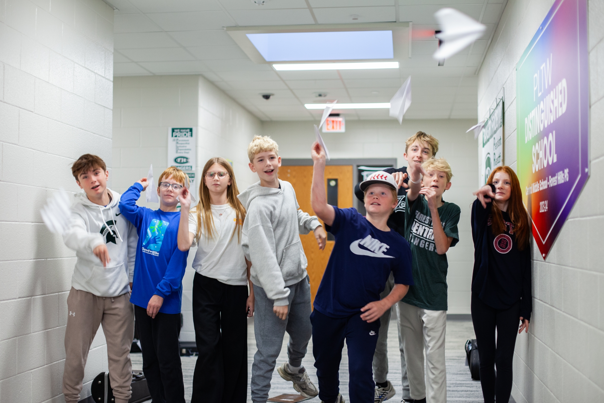 students throwing paper airplanes in a hallway