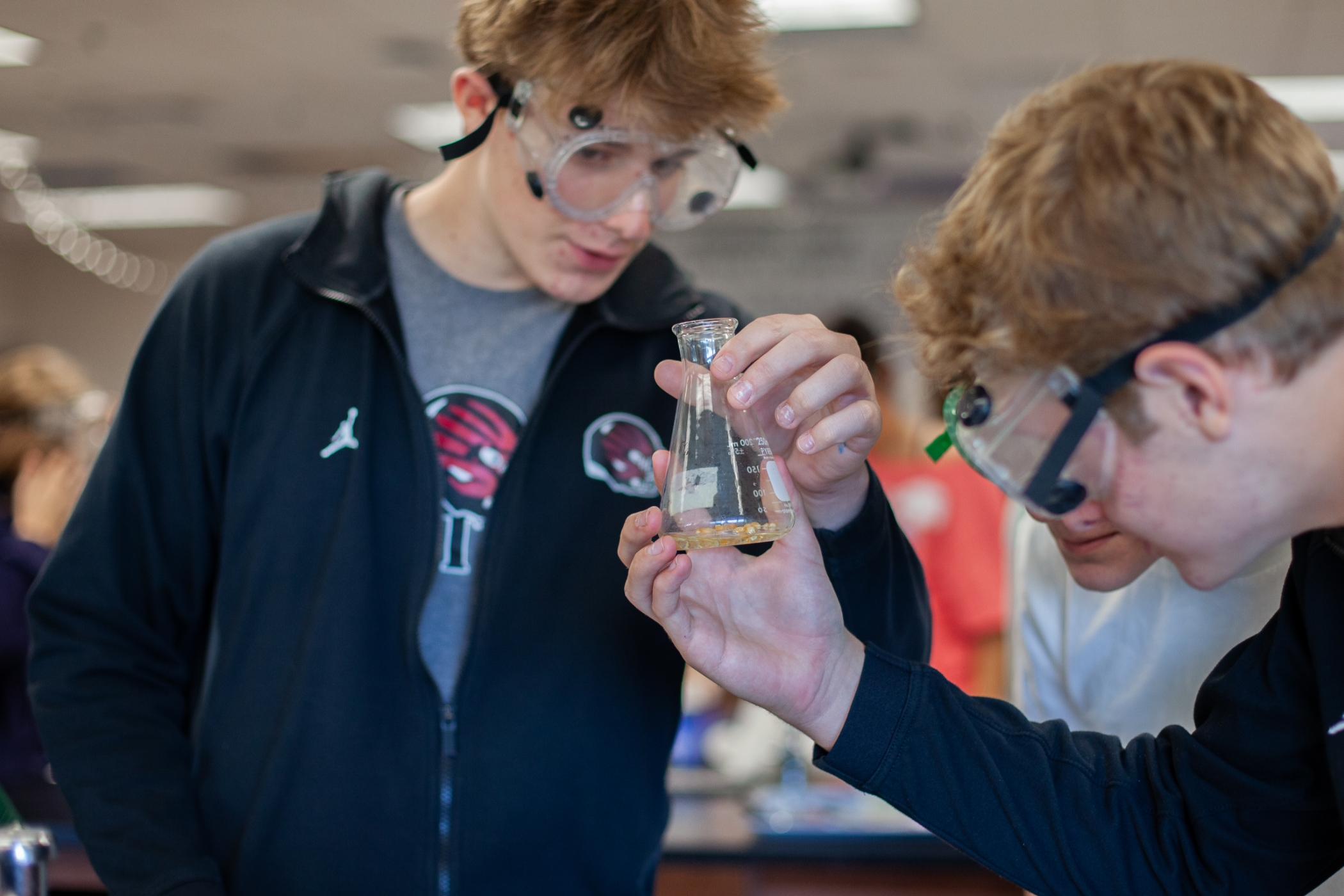 students in a science lab doing something with a beaker