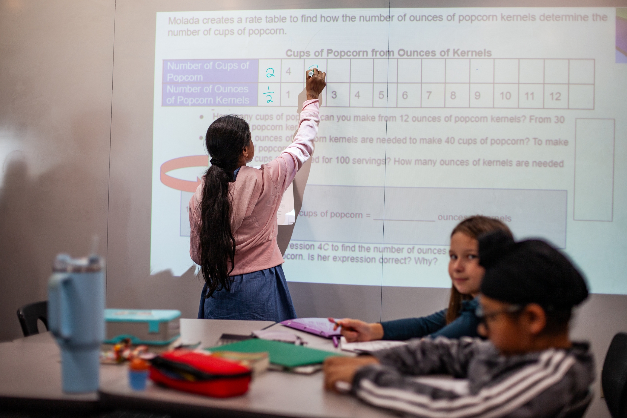 young student working in front of the class on a digital white board