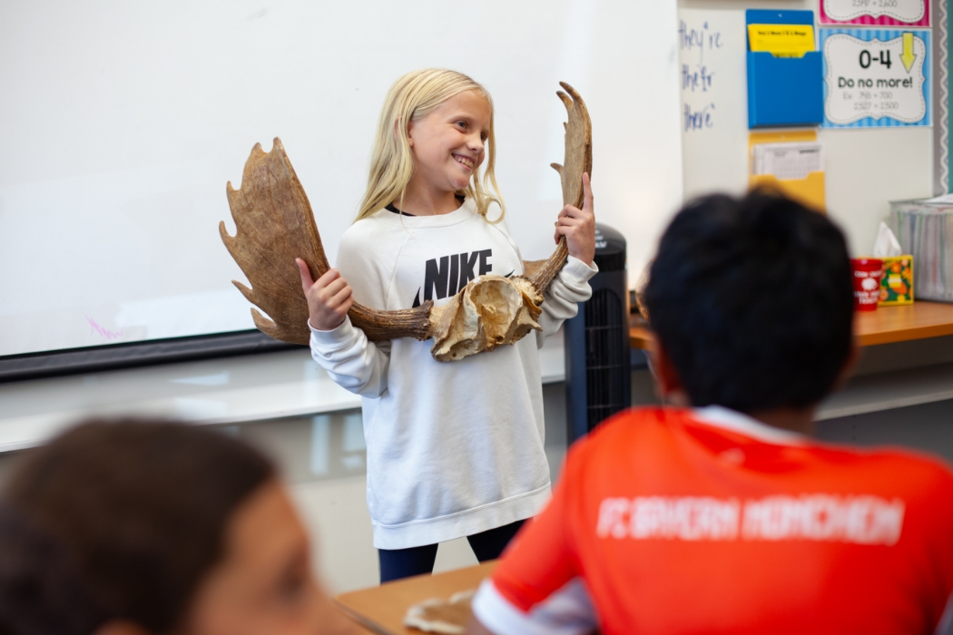 student holding antlers in front of class