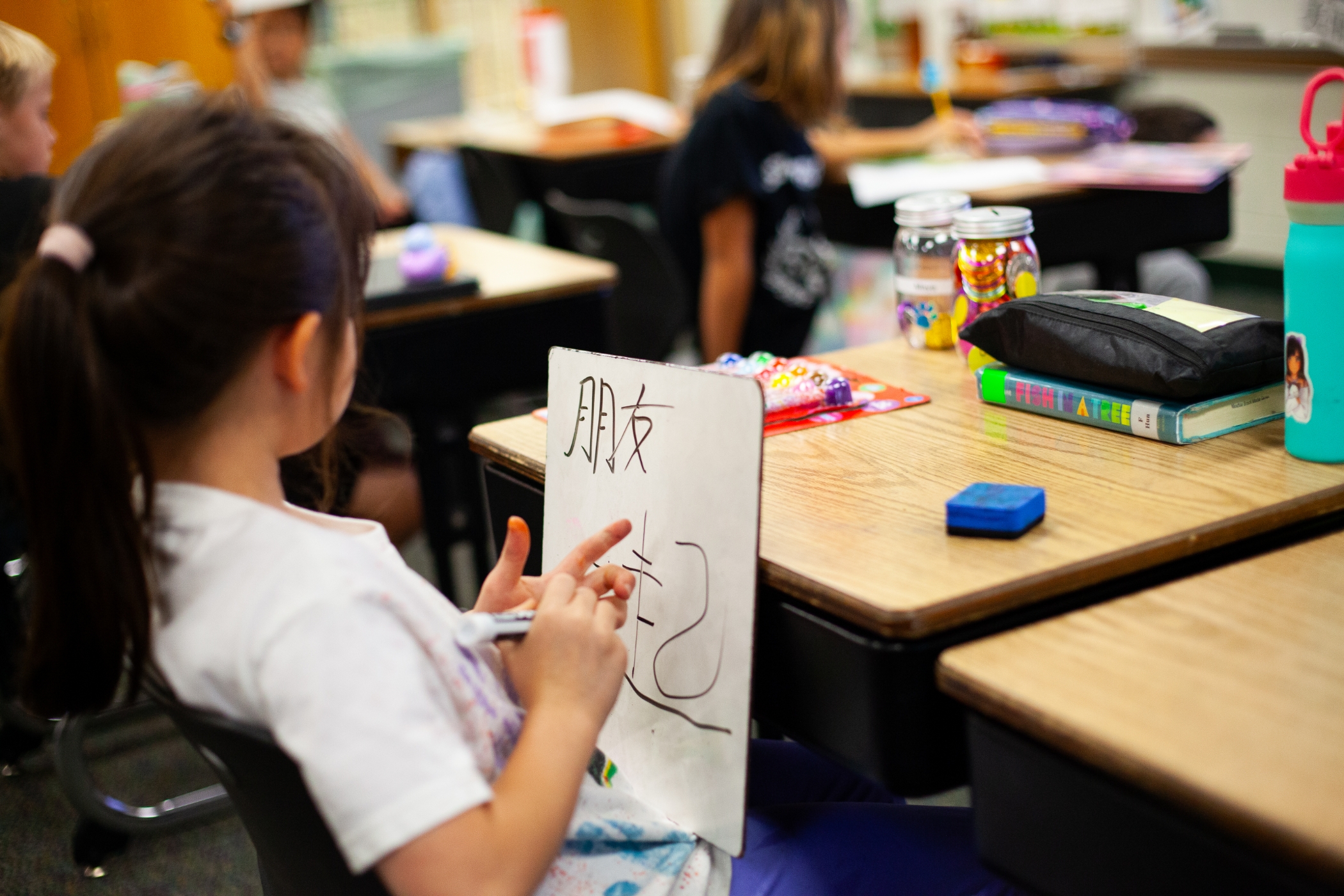 students in class writing asian text on whiteboards