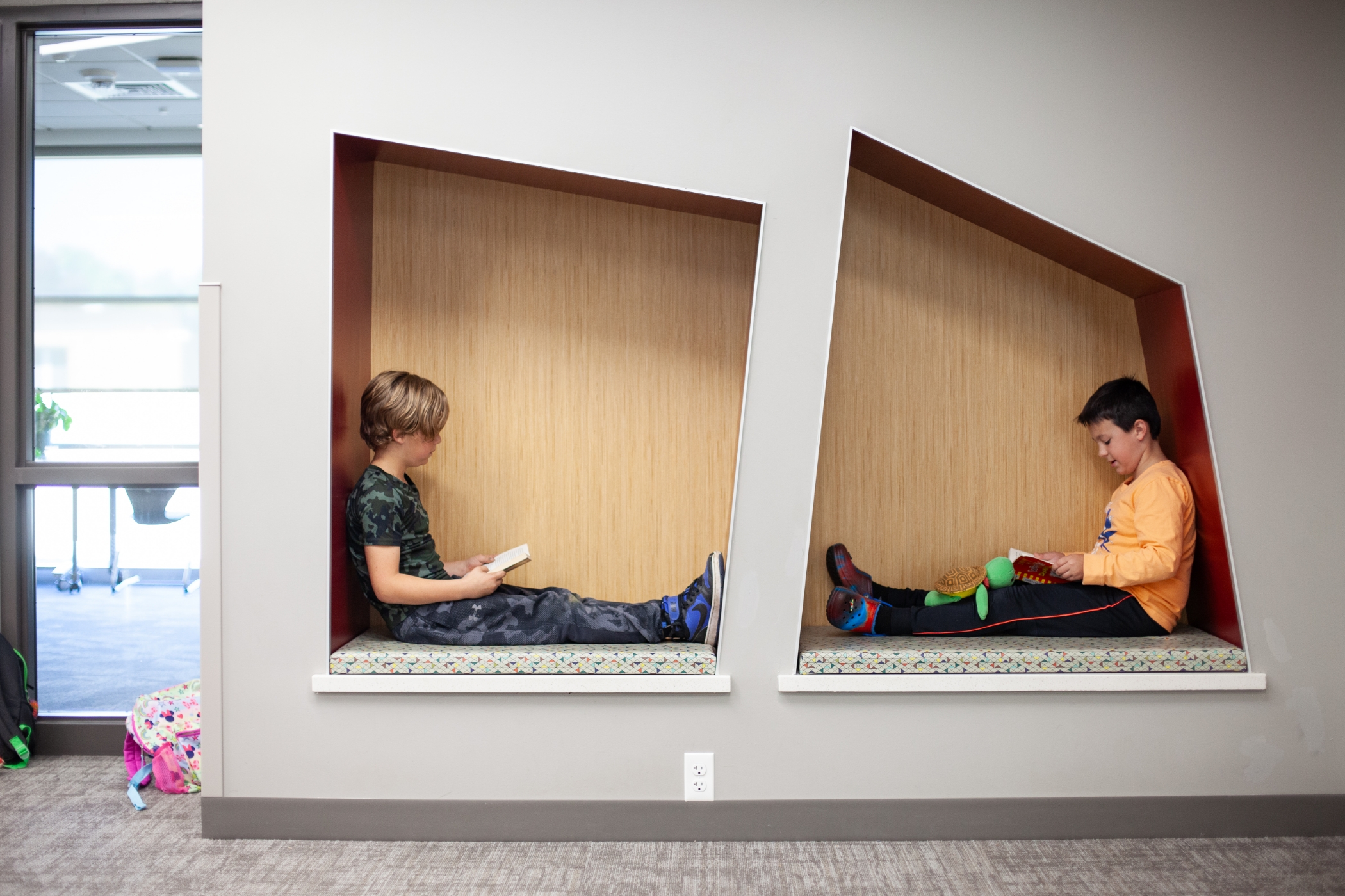 students reading books in cubbies in the wall