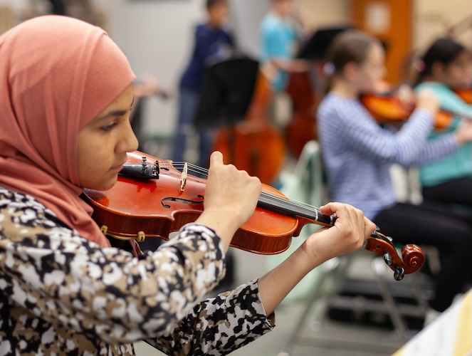student with hijab playing a violin