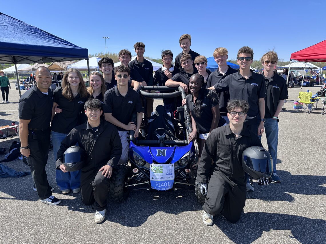 a group of high school students around an electric car shaped like a buggy