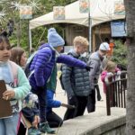 students point to something interesting in an animal habitat at the zoo
