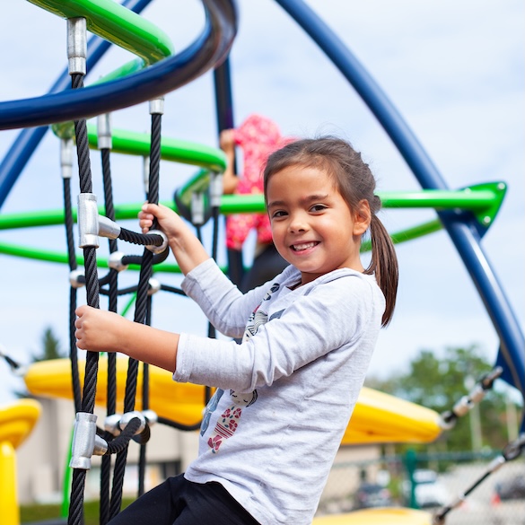 young female student climbing on a jungle gym