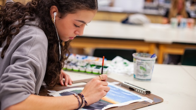 student with earbuds in painting