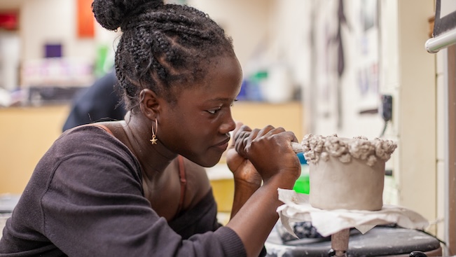 female student working on a clay piece