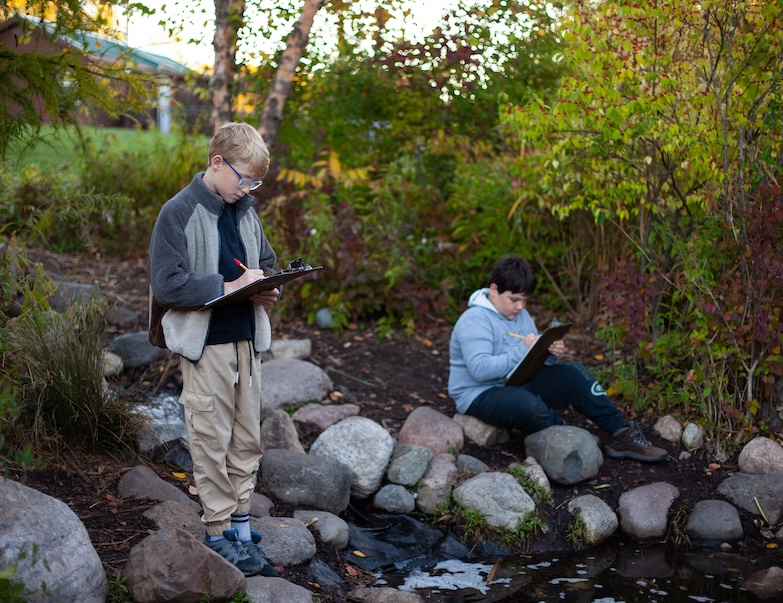 2 students with clipboards in a creek