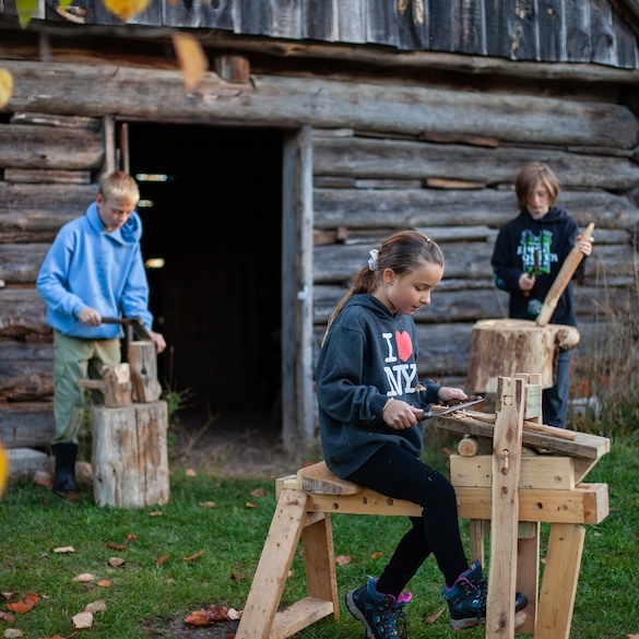three students working outside on wittling projects
