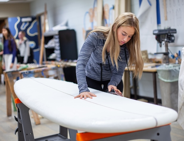 female student sanding a surf board