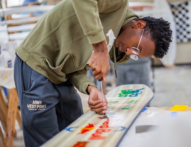 male student working on a snowboard