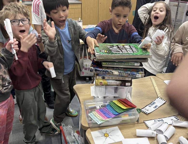 young students stacking heavy books on a paper structure they designed