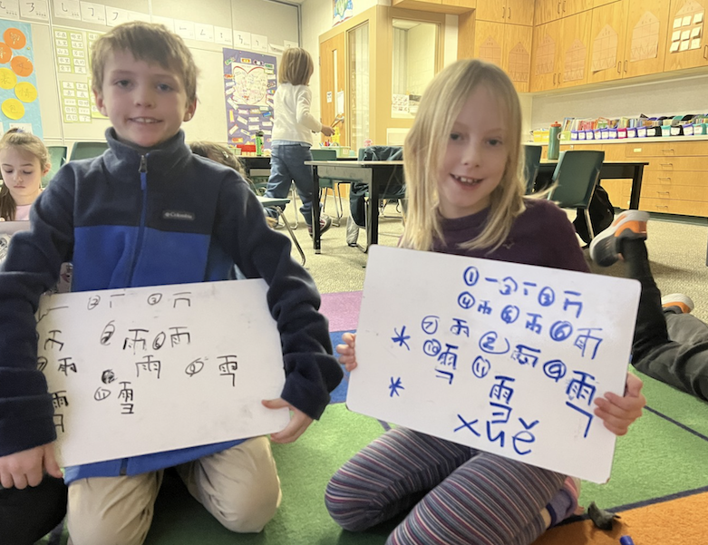 young students showing what they wrote on their whiteboards in mandarin immersion class