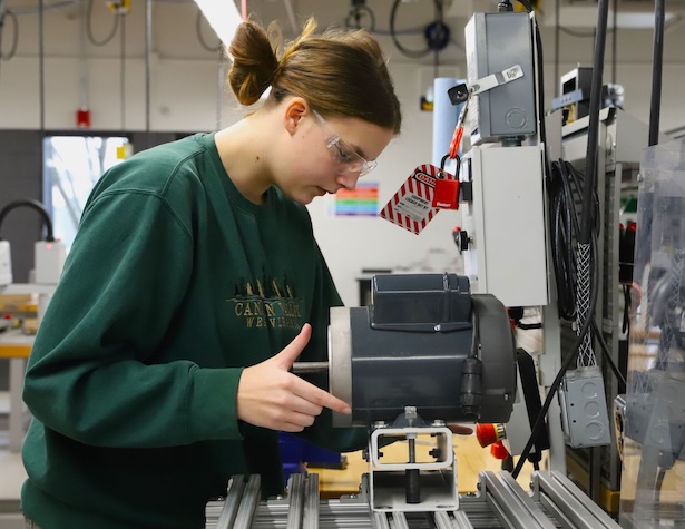female student in a shop class using a motor to design something