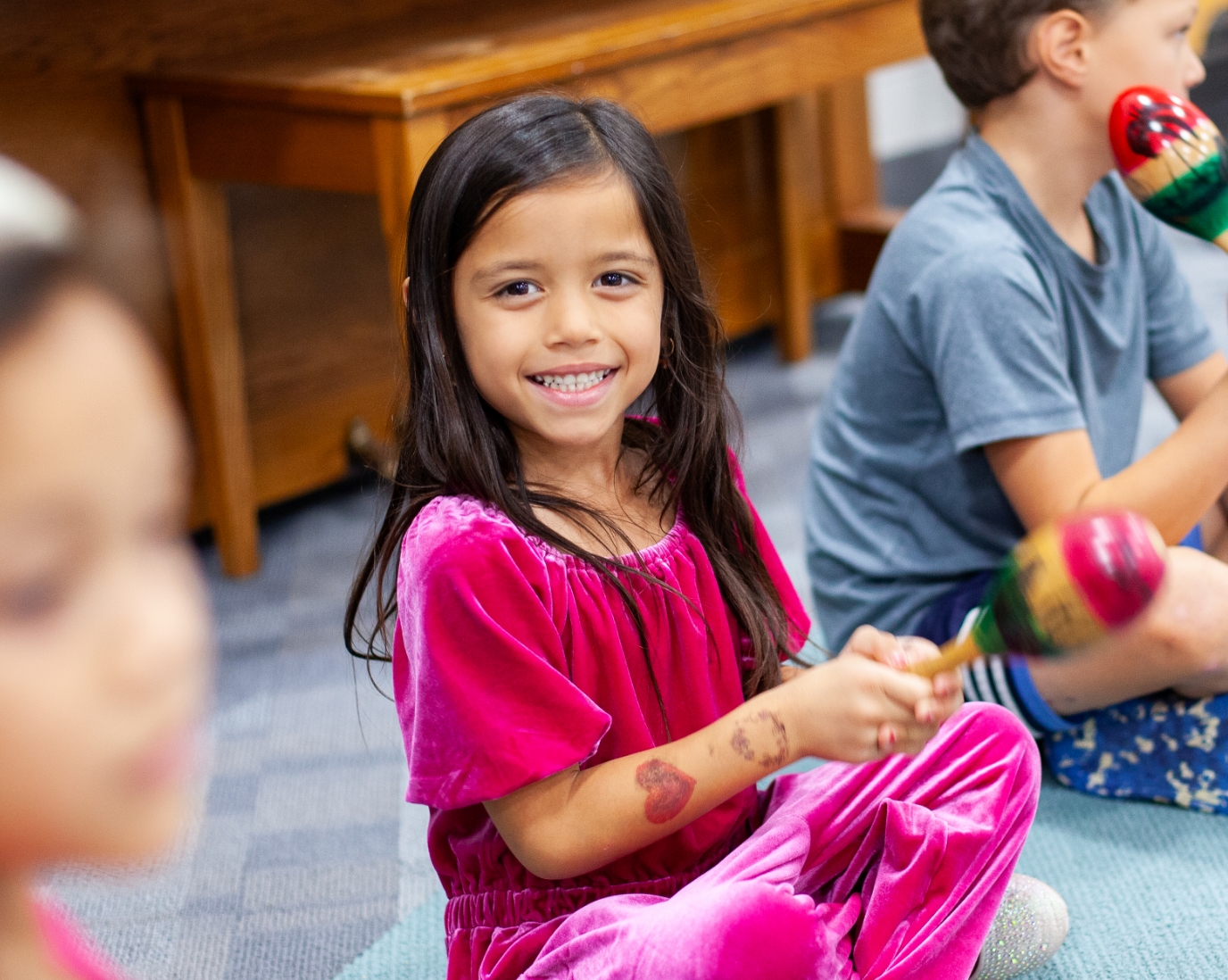young girl student smiling in class and shaking maraca