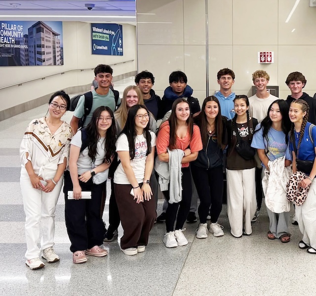 Students posing for a picture together in an airport