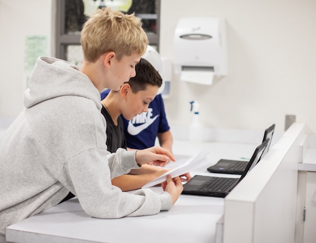 two male students working on a paper airplane