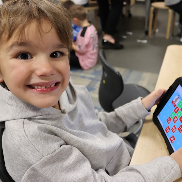 student smiling and showing his Ipad and the program he's using