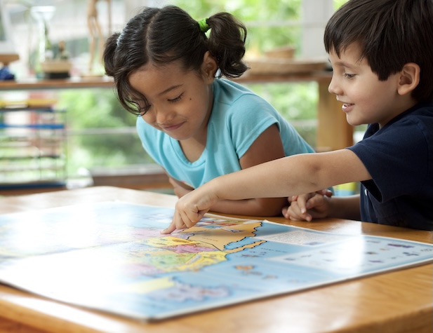 two young students looking at a map and the boy pointing at something on the map