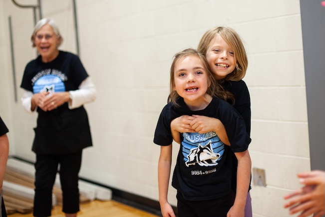 a student helping another student stand up and smiling
