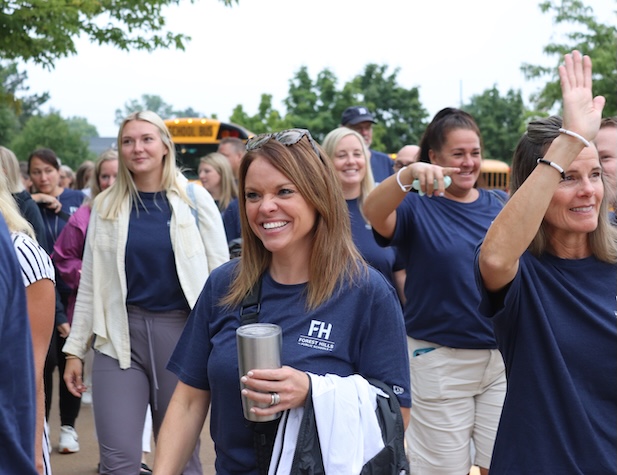 Teachers and staff smiling and walking in a parade