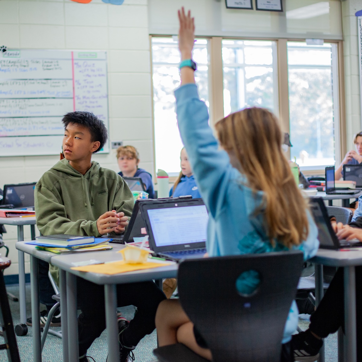 students in a class with one student raising her hand