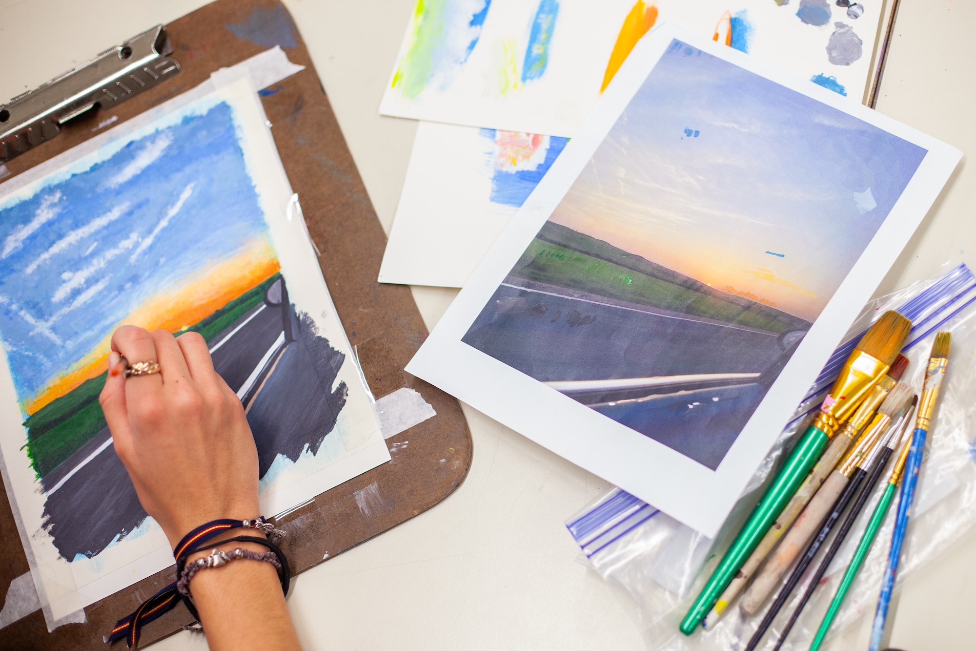 student painting a sunset scene in class