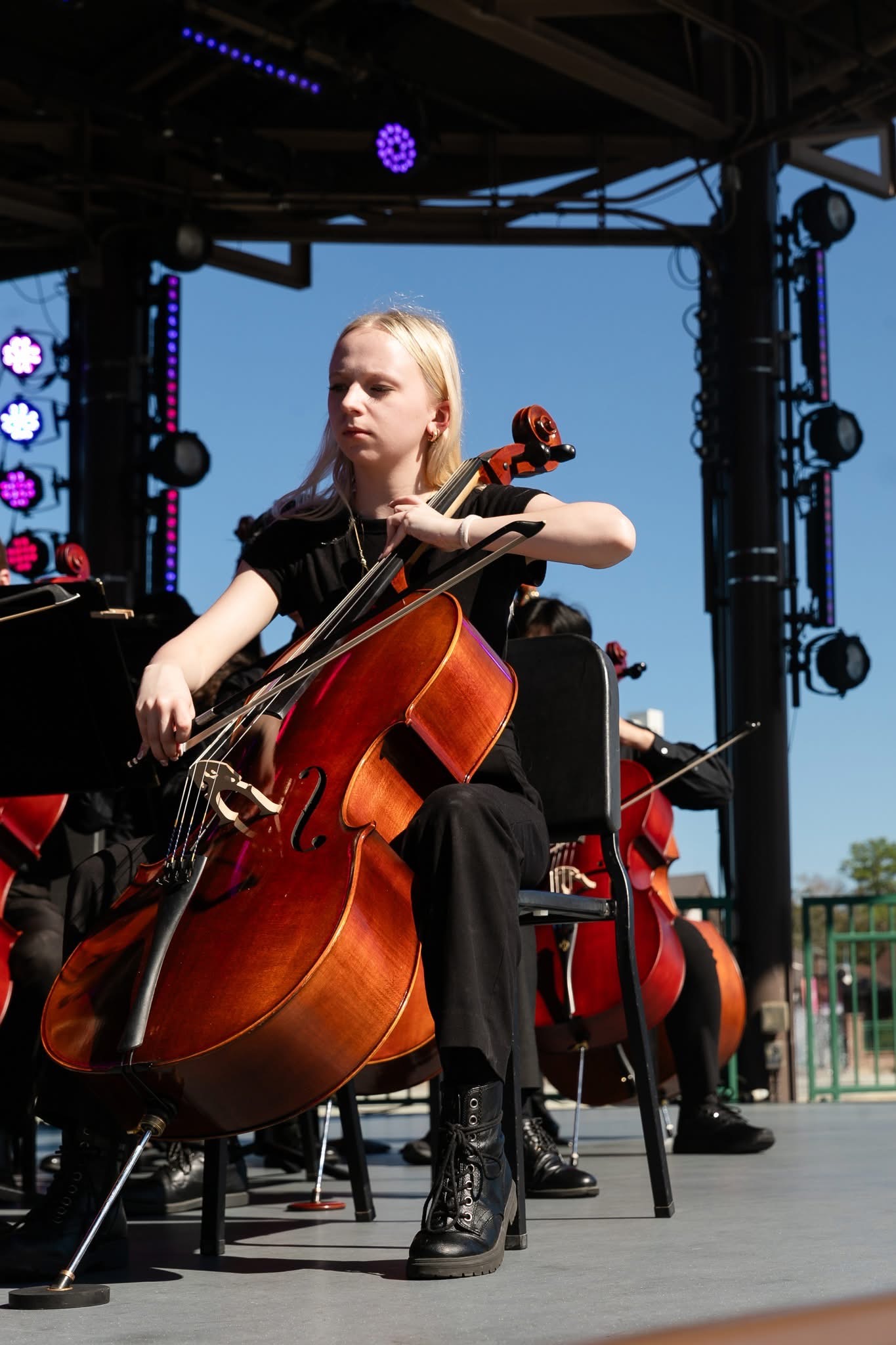 cellist player in an orchestra performing in an outdoor amphitheater