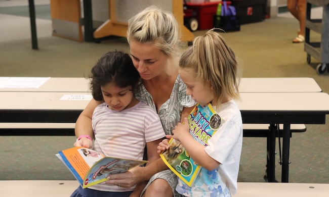 very young female students learning to read with a teacher