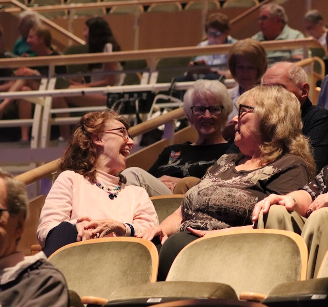 audience members smiling and laughing as they watch a performance